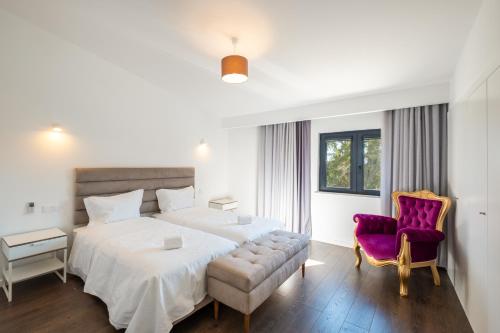 a bedroom with a large bed and a purple chair at Villa Belo Horizonte in Porches