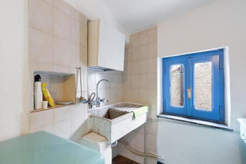 eine Küche mit einem Waschbecken und einem blauen Fenster in der Unterkunft Villa Luisa in Vezzi Portio