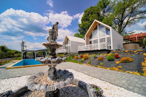 een fontein midden in een tuin met een huis bij Bieszczadzkie Anioły Domki całoroczne in Paszowa