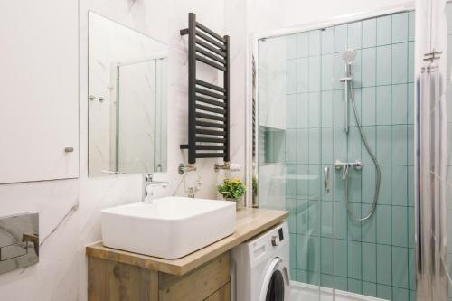 La salle de bains est pourvue d'un lavabo, d'une douche et d'un miroir. dans l'établissement East Street Apartamenty, à Łódź