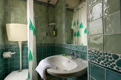a green tiled bathroom with a sink and a mirror at Hotel River fronte mare con piscina in Rimini