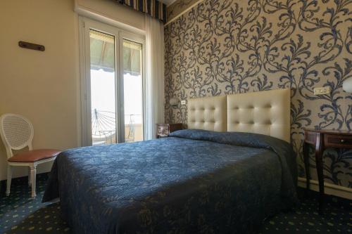una camera da letto con un letto con una coperta blu e una finestra di Hotel River fronte mare con piscina a Rimini