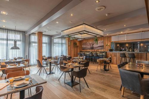 een restaurant met tafels en stoelen en een bar bij Strandhotel Camperduin in Schoorl