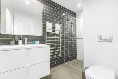 uma casa de banho com um WC, um lavatório e um chuveiro em 3 Bed Hobsonville Point Enchanter - WiFi - Netflix em Auckland
