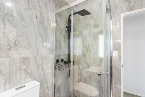 a shower with a glass door in a bathroom at Modern 5BR in Mangere - 6 mins from the Airport in Auckland