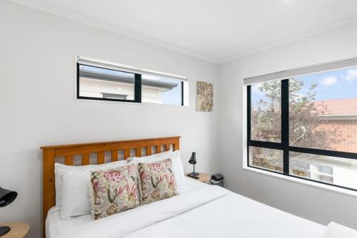 a white bedroom with a bed and a window at Modern 5BR in Mangere - 6 mins from the Airport in Auckland