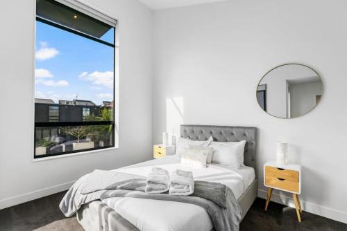 1 dormitorio con cama con espejo y ventana en 3 Bed Hobsonville Point Enchanter - WiFi - Netflix, en Auckland
