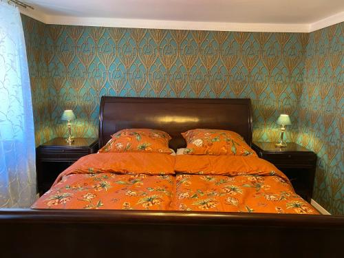 a bedroom with a bed with orange sheets and two lamps at Apartment an der Mosel 2 in Graach