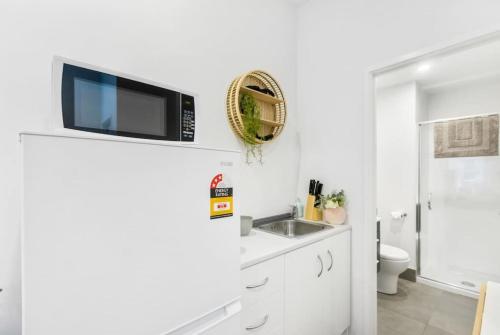een witte badkamer met een wastafel en een toilet bij Gorgeous Studio - Heart of Avondale - Netflix WiFi in Auckland