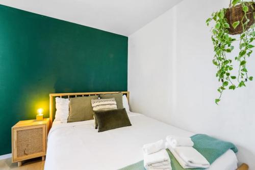 um quarto com uma cama com uma parede verde em City Seaview Stunner with Pool and Gym em Auckland