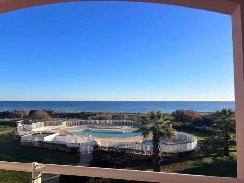 vista su un resort con piscina e oceano di Face à la belle bleue - Appart avec parking a Saint-Cyprien