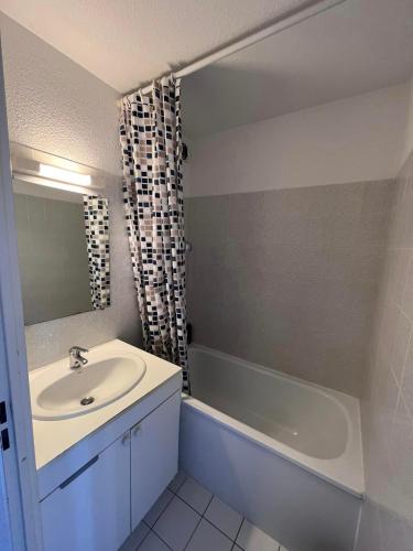 une salle de bain avec un lavabo et une baignoire dans l'établissement Face à la belle bleue - Appart avec parking, à Saint-Cyprien