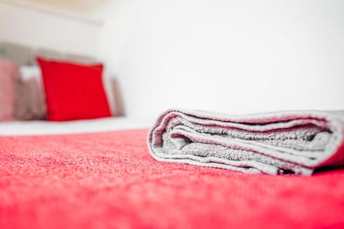 a white towel sitting on top of a red bed at Laid-back Midtown Retreat in Liverpool