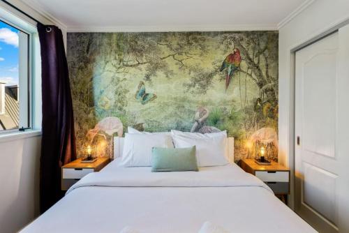 a bedroom with a large bed with a painting on the wall at 3 Bedroom Stunner in Hobsonville - WiFi - Netflix in Auckland
