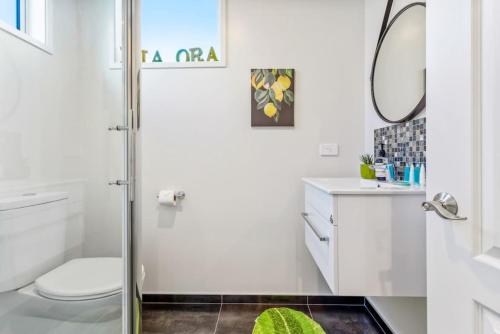 a bathroom with a shower and a toilet and a mirror at 3 Bedroom Stunner in Hobsonville - WiFi - Netflix in Auckland