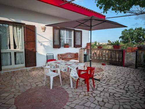 a patio with a table and chairs and an umbrella at Villa Nel Verde - Bonsignore in Tricase