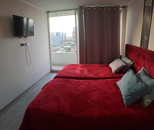 a red bed in a room with a window at Departamento equipado (santiago) in Santiago