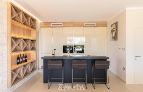 a kitchen with a black island with bar stools at Villa Alessandro in Kringa