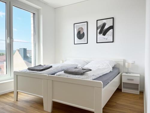 een wit bed in een witte kamer met een raam bij Moderne Apartments im Herzen der Stadt I private Tiefgarage mit Ladesäulen I home2share in Ibbenbüren