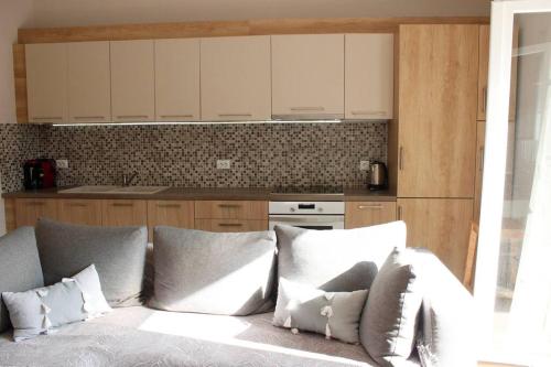 una cucina con armadi bianchi e un divano con cuscini di inHeart Apartment Chios a Chio (Chios)