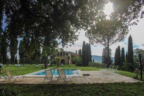 a pool with chairs and a house in the background at Agriturismo Quarantallina in Buonconvento