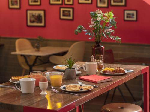 a table with breakfast foods and a vase of flowers at Hôtel Exquis in Paris
