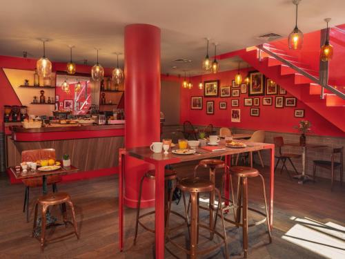 a restaurant with red walls and tables and a staircase at Hôtel Exquis in Paris