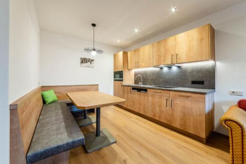 a kitchen with wooden cabinets and a wooden table at Aparthotel Hummerau in Alpbach