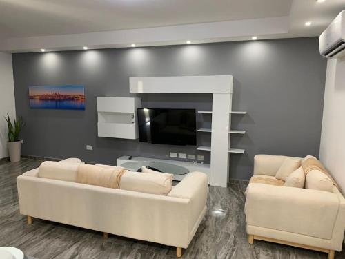 a living room with two white couches and a tv at Spacious and Charming Apartment in Mġarr - 1 in Mġarr