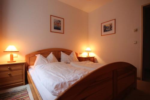 a bedroom with a bed with white sheets and two lamps at Appartement Alpenblick by Schladming-Appartements in Schladming