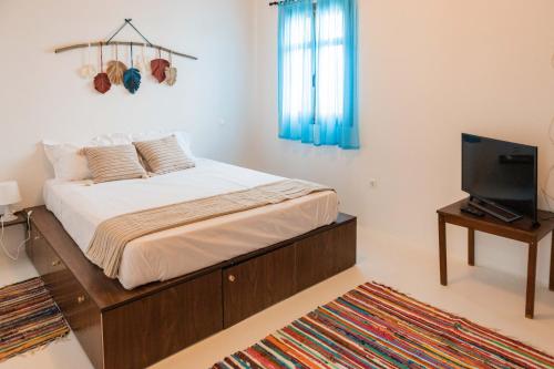 a bedroom with a bed and a flat screen tv at Maria's Traditional Villa in Asklipiḯon