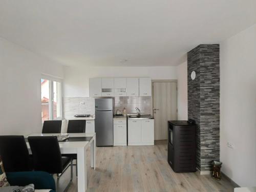 una cucina con mobili bianchi, tavolo e sedie di Apartman Planinski Raj a Žabljak