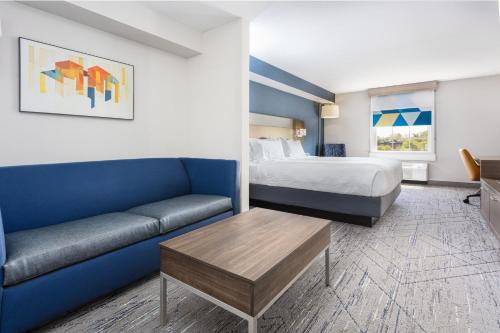 um quarto de hotel com uma cama e um sofá em Holiday Inn Express & Suites Williamsburg, an IHG Hotel em Williamsburg