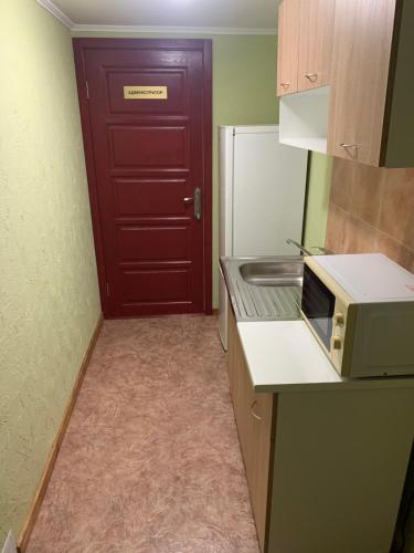 a kitchen with a microwave and a red door at Mega city in Kyiv