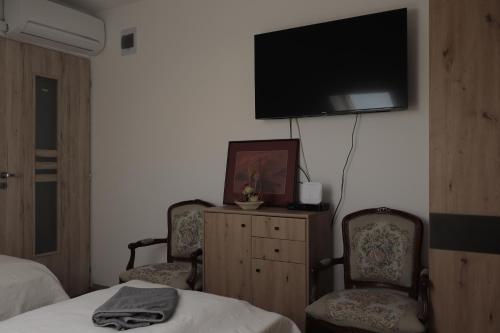 a bedroom with two chairs and a tv on the wall at MaRéJa Vendégház in Hortobágy