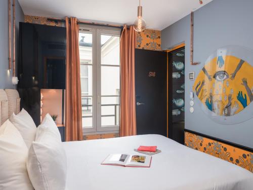 a bedroom with a white bed with a book on it at Hôtel Exquis in Paris