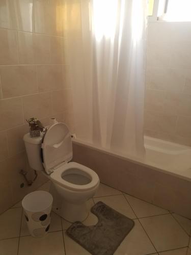 a bathroom with a toilet and a tub with a window at chez albino guest house in São Filipe