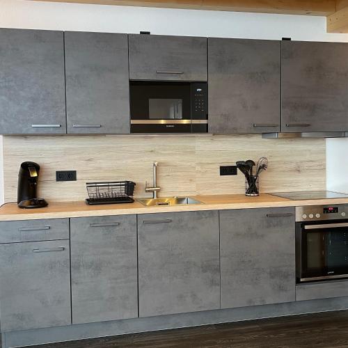 a kitchen with stainless steel cabinets and a microwave at Mountain Moments Tannheim - Familie Weber in Tannheim
