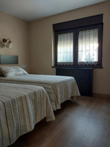 a bedroom with two beds and a window at Hotel Rural Cabrales in Carreña de Cabrales 