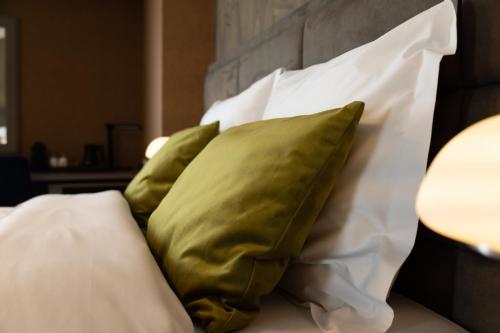 un grupo de almohadas verdes en una cama en Hotel & Restaurant Infinity, en Lichtmis