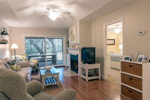 a living room with a couch and a tv at 1135 Summerwind Cottage in Seabrook Island