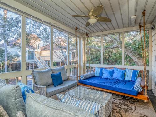 a screened porch with a couch and chairs and a ceiling fan at 779 Spinnaker Beach House in Seabrook Island