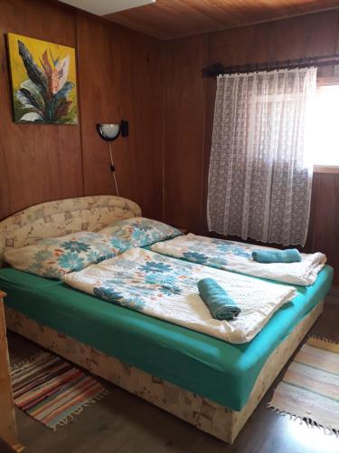 Bett in einem Zimmer mit Fenster in der Unterkunft Zsiga Apartmanház in Balatonszabadi