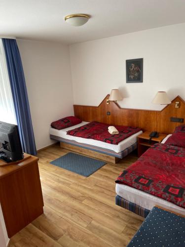 a hotel room with two beds and a television at City Pension in Rastatt