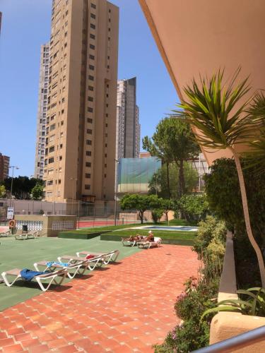 eine Gruppe von Liegestühlen auf einem Tennisplatz mit Gebäuden in der Unterkunft El Apartamento de Cristian 3 in Benidorm