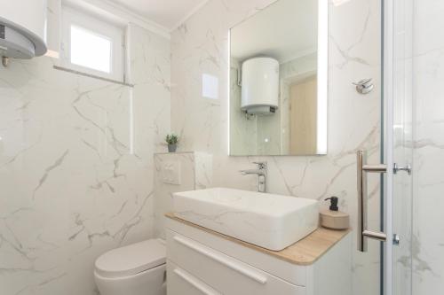 a white bathroom with a sink and a mirror at La casa Gidora in Šibenik