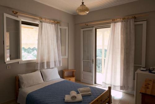 a bedroom with a bed with two hats and two windows at CHRISTINAS STUDIOS NIKIANA in Nikiana