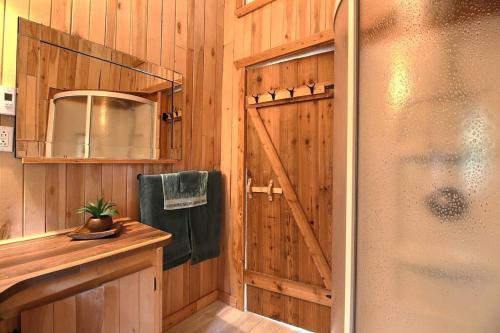 a bathroom with a shower and a wooden wall at Le Chouette Chalet in La Malbaie