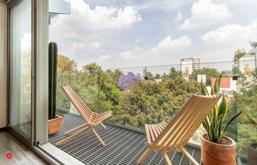 2 sillas en un balcón con vistas a los árboles en Casa Poe by Kukun, en Ciudad de México