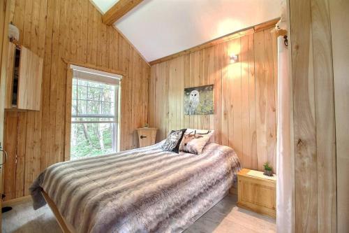 a bedroom with a bed and a window in it at Le Chouette Chalet in La Malbaie